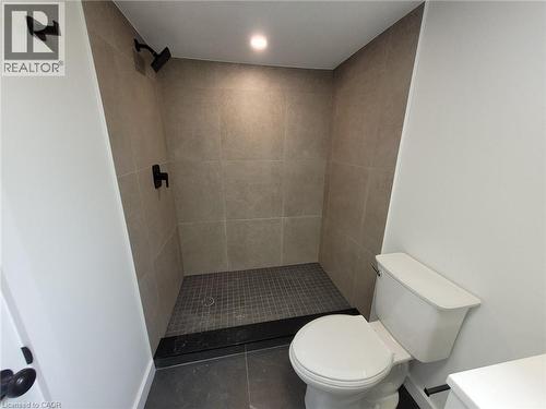 Walk-in shower with large format tile surround and dark mosaic floor - 132 East 31St Street, Hamilton, ON - Indoor Photo Showing Bathroom