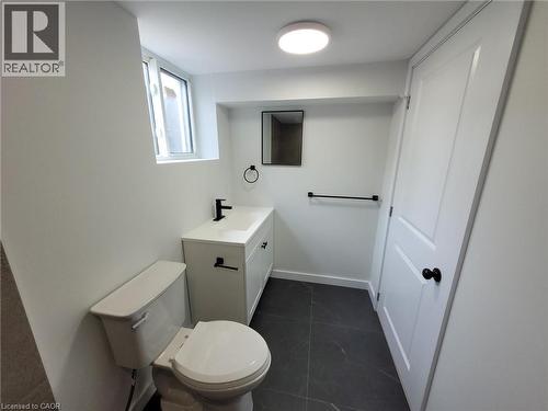 Bathroom featuring a white vanity with integrated sink, matte black fixtures, dark gray tile flooring, a white two-panel door, and a horizontal window - 132 East 31St Street, Hamilton, ON - Indoor Photo Showing Bathroom
