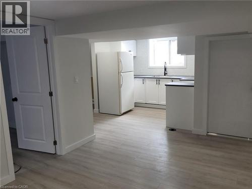 Kitchen area featuring white cabinetry, dark countertops, a white subway tile backsplash, and a white appliance package - 132 East 31St Street, Hamilton, ON - Indoor Photo Showing Kitchen