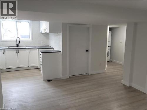 Modern kitchen featuring white cabinetry, dark countertops, a subway tile backsplash, and a black faucet - 132 East 31St Street, Hamilton, ON - Indoor Photo Showing Kitchen