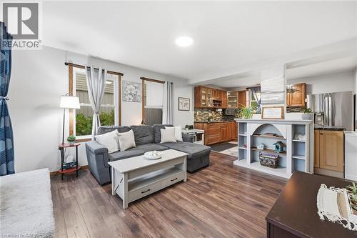 Open-concept living area showcasing wood-finish flooring throughout, a gray upholstered sectional sofa, and a white shelving unit with built-in storage - 450 East 42Nd Street, Hamilton, ON - Indoor Photo Showing Living Room
