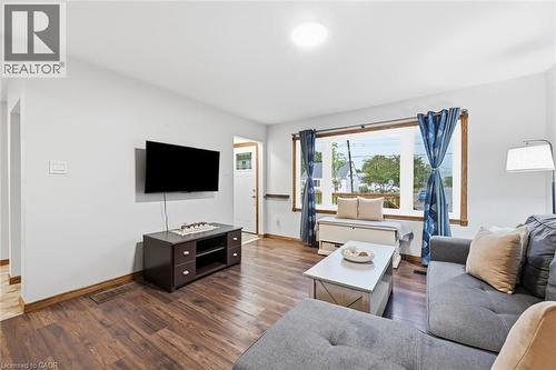 Living area featuring wood-finish flooring, a broad picture window, light-toned walls, and a ceiling-mounted light fixture - 450 East 42Nd Street, Hamilton, ON - Indoor Photo Showing Living Room