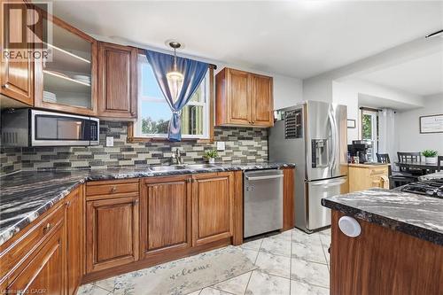 Kitchen featuring wood cabinetry, stainless steel appliances, patterned tile flooring, and a mosaic tile backsplash - 450 East 42Nd Street, Hamilton, ON - Indoor Photo Showing Kitchen