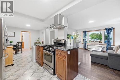 Open-concept kitchen and living area featuring a center island with wood cabinetry, stainless steel gas range with dual ovens, and a modern range hood - 450 East 42Nd Street, Hamilton, ON - Indoor