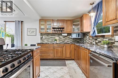 Kitchen with wood cabinetry, stainless steel appliances, mosaic tile backsplash, and patterned tile flooring - 450 East 42Nd Street, Hamilton, ON - Indoor Photo Showing Kitchen With Double Sink