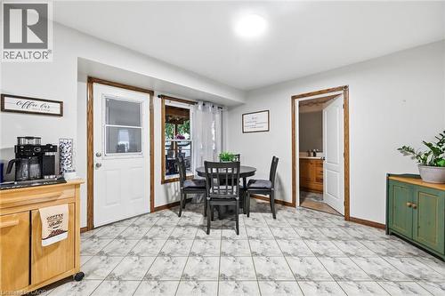 Bright kitchen and dining area featuring ceramic tile flooring, black wood dining table with seating for four, white glass-panel door with wood trim, and wood cabinetry with integrated appliances - 450 East 42Nd Street, Hamilton, ON - Indoor