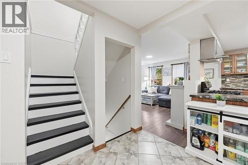 Modern foyer featuring a striking staircase with contrasting black and white treads and a brushed metal handrail, complemented by marble-finish tile flooring - 450 East 42Nd Street, Hamilton, ON - Indoor Photo Showing Other Room