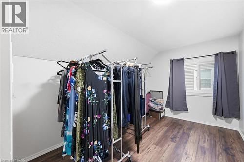Spacious bedroom featuring wood-finish flooring, abundant natural light from dual windows with blackout curtains, and generous closet space with multiple clothing rods for ample storage - 450 East 42Nd Street, Hamilton, ON - Indoor With Storage