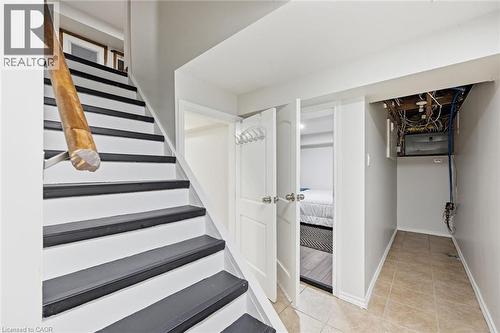 Modern staircase featuring contrasting white and dark gray treads with a sturdy wooden handrail - 450 East 42Nd Street, Hamilton, ON - Indoor Photo Showing Other Room