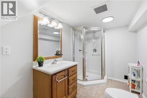 Modern primary bathroom featuring a wood-finish vanity with dual drawers, white countertop, and illuminated mirror with integrated lighting - 450 East 42Nd Street, Hamilton, ON - Indoor Photo Showing Bathroom