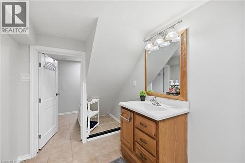 Spa-inspired bathroom featuring a wood-finish vanity with ample storage drawers, white porcelain sink, and brushed metal fixtures - 450 East 42Nd Street, Hamilton, ON - Indoor Photo Showing Bathroom