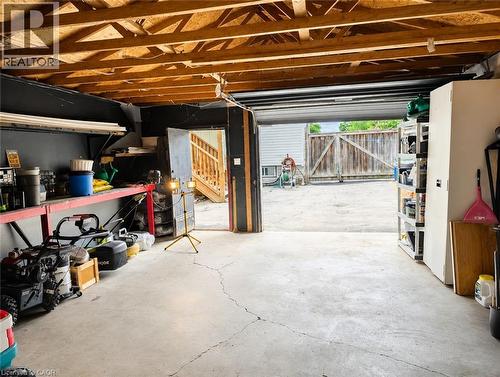 Spacious garage featuring exposed beam ceiling, concrete flooring, built-in wall shelving, overhead garage door with natural light, and ample storage capacity for vehicles and equipment - 450 East 42Nd Street, Hamilton, ON - Indoor
