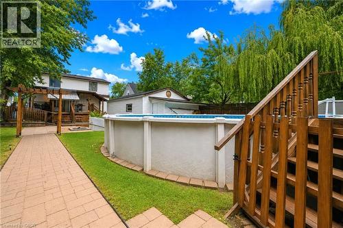 Wooden steps providing access to the above-ground pool, complemented by a paver walkway, lush green lawn, and a wooden pergola structure - 450 East 42Nd Street, Hamilton, ON - Outdoor With Above Ground Pool