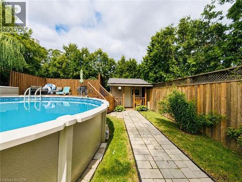 Backyard oasis featuring an above-ground saltwater pool with integrated ladder and deck surround, complemented by a stone paver pathway, wooden privacy fencing, a detached pool house with covered entr - 450 East 42Nd Street, Hamilton, ON - Outdoor With Above Ground Pool