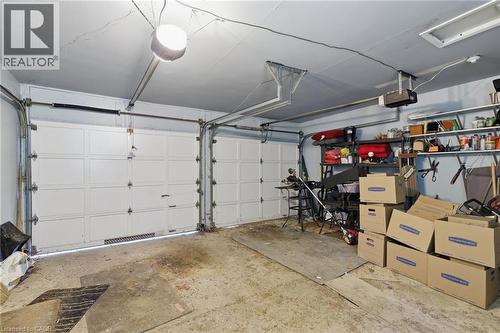 Spacious two-car garage featuring white paneled doors, concrete flooring, overhead lighting, wall-mounted storage shelving with organized bins, and ample room for vehicles and additional storage needs - 356 Thompson Road, London, ON - Indoor Photo Showing Garage