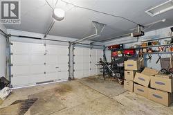 Spacious two-car garage featuring white paneled doors, concrete flooring, overhead lighting, wall-mounted storage shelving with organized bins, and ample room for vehicles and additional storage needs - 