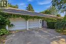 Spacious two-car garage with white panel doors and concrete driveway, framed by mature landscaping and lush green foliage - 356 Thompson Road, London, ON  - Outdoor 