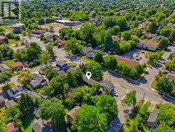 Aerial perspective of a residential neighborhood featuring mature trees, paved streets, and a mix of single-family homes and multi-story buildings - 