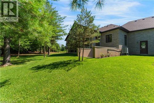 Expansive green lawn with mature evergreen trees and a stone-clad exterior - 986 Highway 8, Hamilton, ON - Outdoor