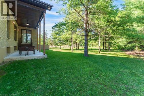 Expansive grounds featuring a meticulously manicured lawn anchored by mature shade trees, with a brick exterior and covered patio area ideal for outdoor entertaining and relaxation - 986 Highway 8, Hamilton, ON - Outdoor
