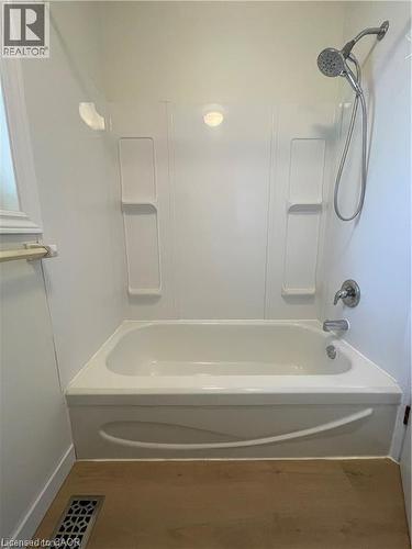 Clean and functional bathroom featuring a built-in soaking tub with integrated deck-mounted faucet and handheld showerhead, white subway tile surround with recessed shelving for storage, chrome fixtur - 683 Coronation Boulevard Unit# 2, Cambridge, ON - Indoor Photo Showing Bathroom