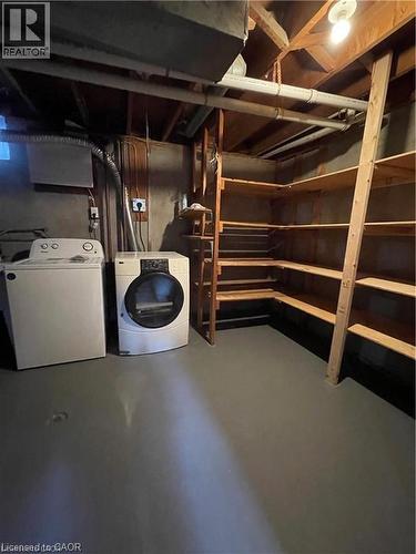 Utility room featuring stackable washer and dryer units, polished concrete flooring, wooden shelving with multiple storage tiers, recessed lighting, and exposed ceiling infrastructure - 683 Coronation Boulevard Unit# 2, Cambridge, ON - Indoor Photo Showing Laundry Room