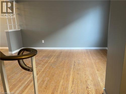 Spacious room showcasing warm wood-finish flooring throughout, neutral gray walls, and abundant natural light from multiple windows - 683 Coronation Boulevard Unit# 2, Cambridge, ON - Indoor Photo Showing Other Room