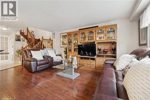 Spacious living area showcasing rich wood-finish flooring, custom built-in cabinetry with glass-front display storage, and a media center - 86 Bridlewreath Street, Kitchener, ON - Indoor Photo Showing Living Room
