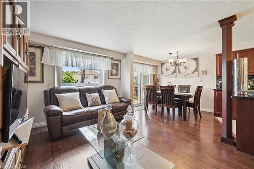 Open-concept living space featuring hardwood flooring throughout, a brown leather sectional sofa, and a glass-top cocktail table - 86 Bridlewreath Street, Kitchener, ON - Indoor