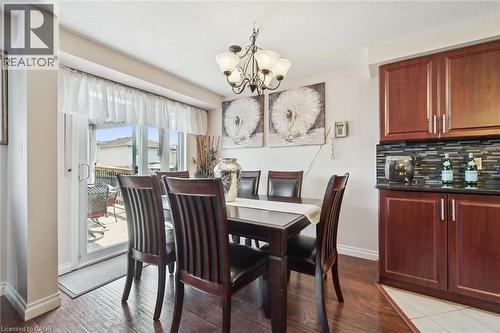 Elegant dining area showcasing rich wood-finish flooring, a dark wood dining table with upholstered chairs, and warm ambient lighting from a brass chandelier - 86 Bridlewreath Street, Kitchener, ON - Indoor Photo Showing Dining Room