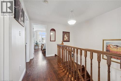 Hallway with rich wood-finish flooring, white walls, and a traditional wood baluster staircase - 86 Bridlewreath Street, Kitchener, ON - Indoor Photo Showing Other Room