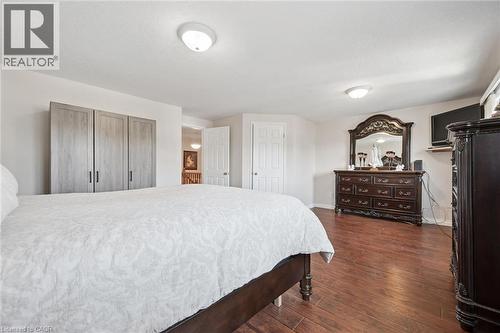 Spacious primary bedroom showcasing hardwood flooring, recessed ceiling lighting, and extensive built-in closet storage with light wood-finish cabinetry - 86 Bridlewreath Street, Kitchener, ON - Indoor Photo Showing Bedroom