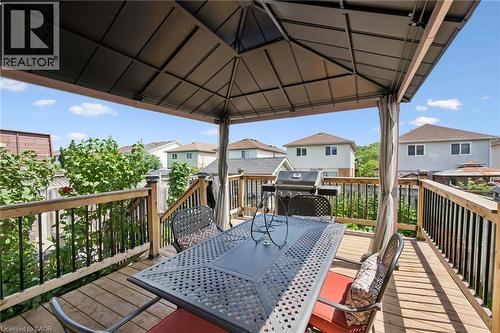 Expansive composite deck featuring a substantial metal-framed pergola with integrated shade panels, stamped concrete decking with decorative border detailing, and black metal railings - 86 Bridlewreath Street, Kitchener, ON - Outdoor With Deck Patio Veranda With Exterior