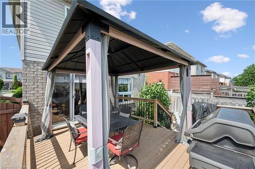 Expansive outdoor wood-finish deck featuring a built-in gazebo with drapes, black metal railing, and solar-powered post caps - 86 Bridlewreath Street, Kitchener, ON - Outdoor With Deck Patio Veranda With Exterior