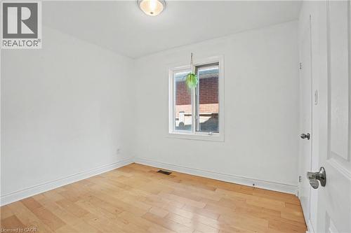 Bright room featuring wood-finish flooring, white walls, and a window with white trim - 100 Hardale Crescent, Hamilton, ON - Indoor Photo Showing Other Room