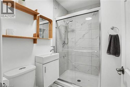 Compact bathroom featuring a glass-enclosed shower with white marble-patterned tile, a wall-mounted vanity with a rectangular sink, and chrome fixtures - 100 Hardale Crescent, Hamilton, ON - Indoor Photo Showing Bathroom