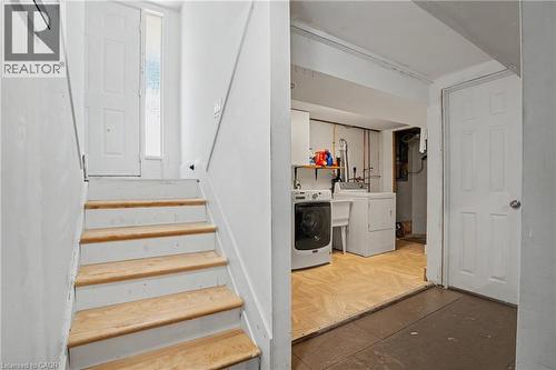 Lower level laundry area with parquet-style flooring and utility sink - 100 Hardale Crescent, Hamilton, ON - Indoor
