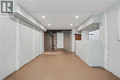 Unfinished basement space featuring recessed lighting, a utility door, exposed block walls, and a barn door entry - 100 Hardale Crescent, Hamilton, ON - Indoor Photo Showing Other Room