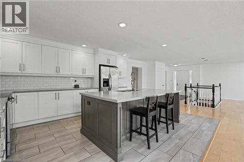 Expansive kitchen featuring a large central island with seating, white shaker cabinetry, stainless steel appliances, and a subway tile backsplash - 100 Hardale Crescent, Hamilton, ON - Indoor Photo Showing Kitchen With Upgraded Kitchen
