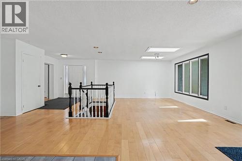 Expansive open-concept room featuring light wood-finish flooring, a black and white staircase balustrade, multiple recessed lights, and two skylights - 100 Hardale Crescent, Hamilton, ON - Indoor Photo Showing Other Room