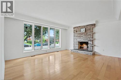 Stone-clad fireplace feature with an expansive five-panel window and wood-finish flooring - 100 Hardale Crescent, Hamilton, ON - Indoor Photo Showing Living Room With Fireplace