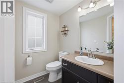 Spa-inspired bathroom featuring a curved oval sink with widespread faucet, wood-finish vanity with ample storage, large framed mirror with integrated lighting, and neutral tile finishes - 