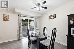 Dining area with wood-finish flooring, ceiling fan with integrated lighting, and direct access to an outdoor deck through sliding glass doors - 