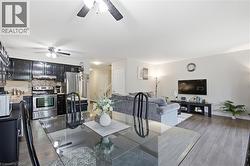 Open-concept living space featuring stainless steel appliances, dark cabinetry with gas range, wood-finish flooring throughout, and seamless integration of kitchen and living areas - 
