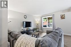 Living area featuring light-toned walls, wood-finish flooring, and a large window with a rear property outlook - 