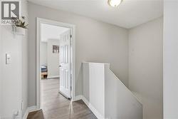 Bright upper-level hallway featuring white painted walls, wood-finish flooring, and clean white trim details - 