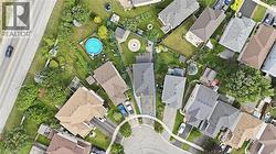 Aerial view of a well-appointed residential community featuring multiple single-family homes with varied architectural styles, manicured lawns, mature landscaping, and a sparkling resort-style swimmin - 