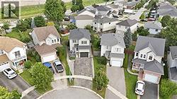 Aerial view showcasing a two-story residence with a modern architectural design, featuring a dark-toned asphalt driveway, attached two-car garage, and manicured landscaping with mature trees - 