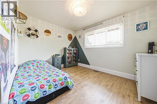 Hardwood-finish flooring extending throughout, a large window with horizontal blinds, and a built-in ceiling light fixture - 364 Fennell Avenue W, Hamilton, ON - Indoor Photo Showing Bedroom