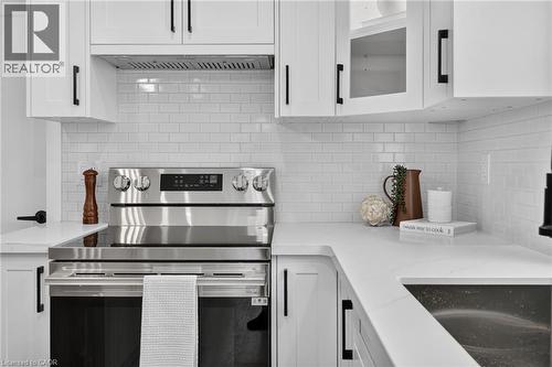 Stainless steel range with a flat cooktop, white shaker cabinetry, white subway tile backsplash, white countertops, and a stainless steel under-mount sink - 325 Queensdale Avenue E, Hamilton, ON - Indoor Photo Showing Kitchen